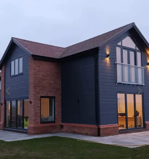 Dark cladding beside red brick — CG Cladding Solutions